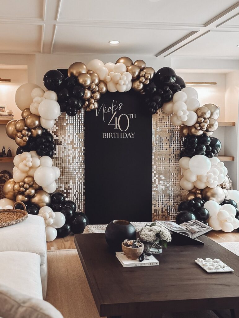 Balloon arch in black, gold, and white surrounding a 40th birthday backdrop.