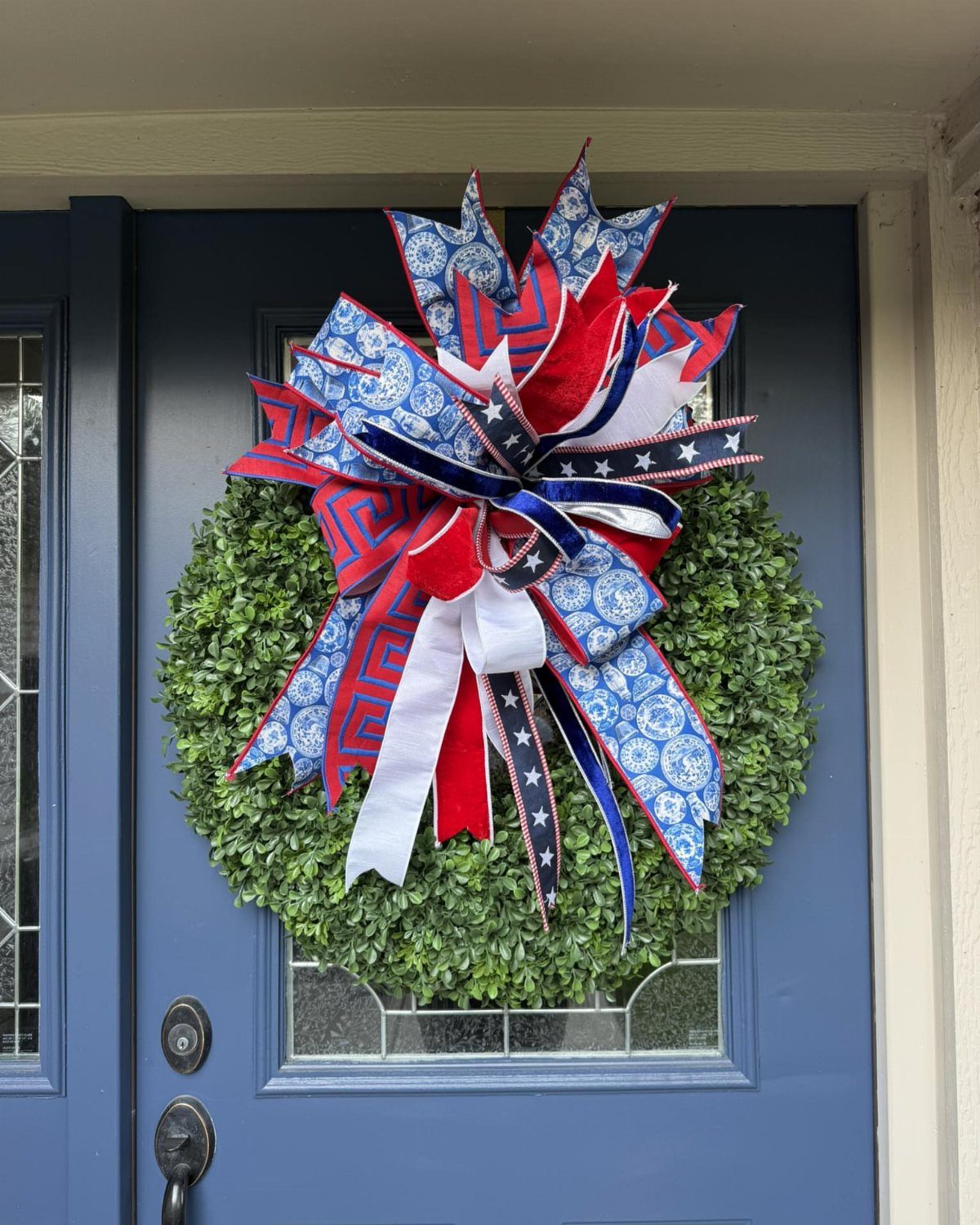 Patriotic red, white, and blue bow on a green wreath on a blue door
