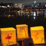 Three glowing yellow paper lanterns with drawings of Totoro and Snoopy at night
