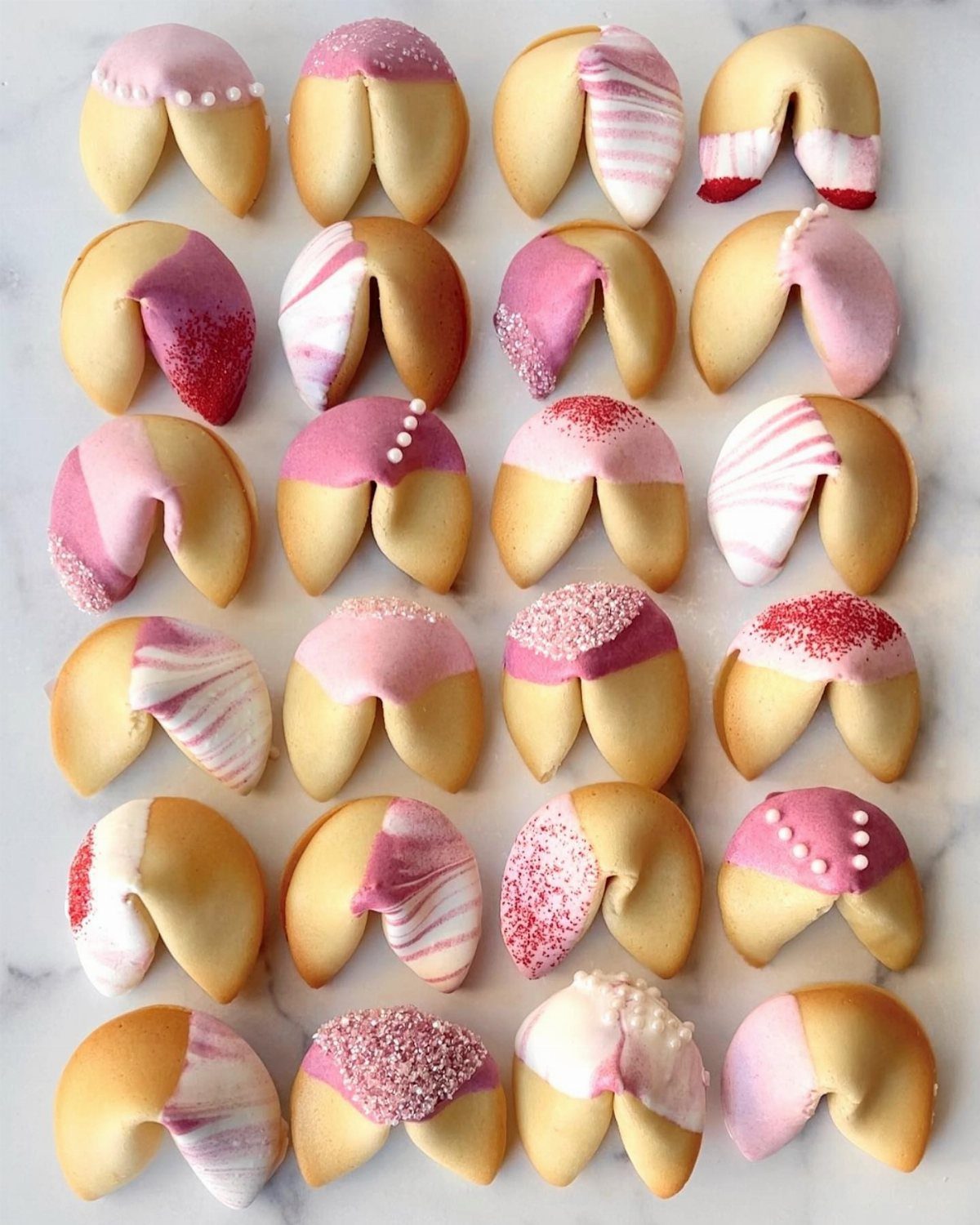 Decorated fortune cookies with pink icing and sprinkles on a marble background