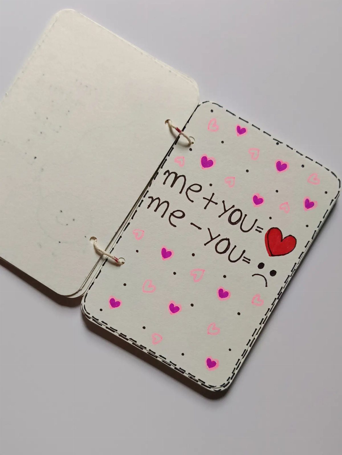 Handmade white notebook with heart drawings and romantic math equations on the cover.