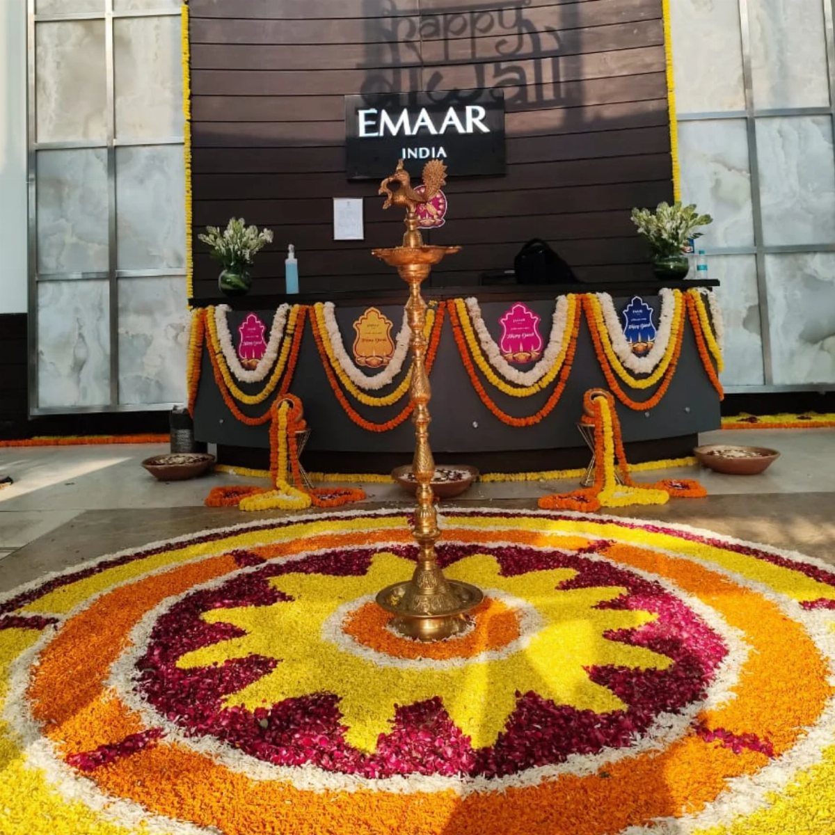 Colorful flower rangoli and brass lamp in an office decorated for Diwali