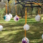 Eyeball ornaments hanging from a large black spider web in a grassy yard