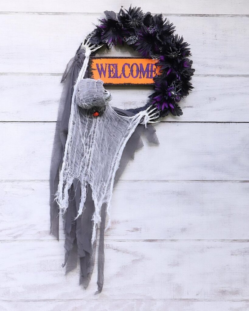 Halloween wreath with skeleton hands, a ghostly figure, and a welcome sign.