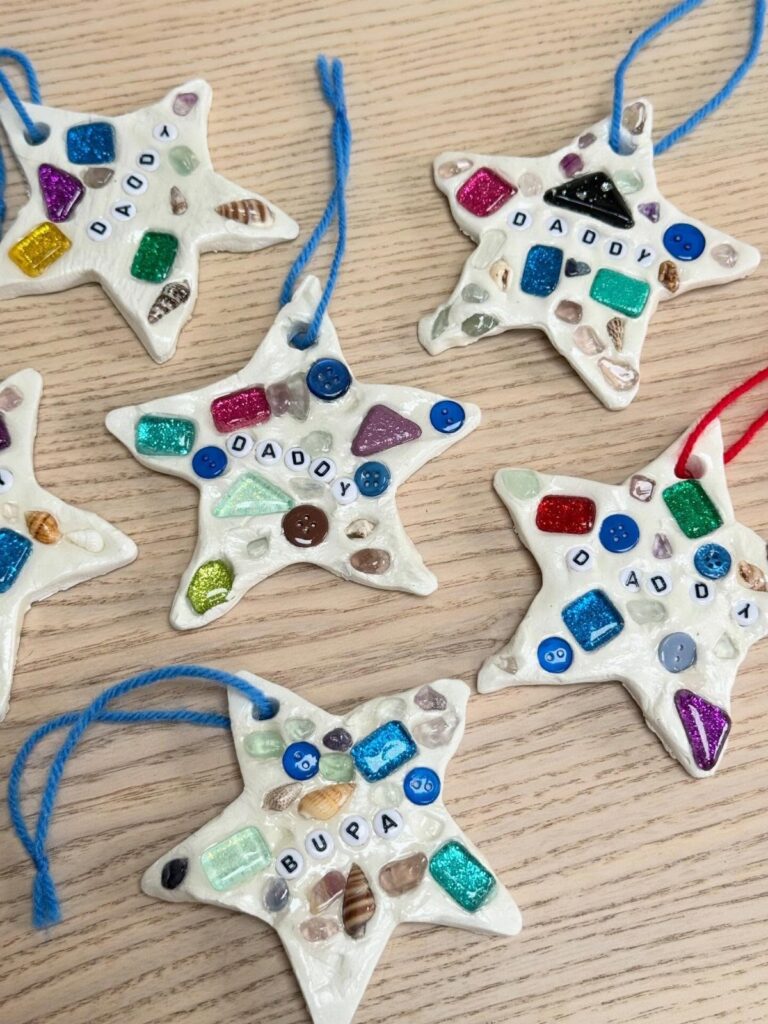 Star-shaped salt dough ornaments decorated with colorful glass gems and letter beads.