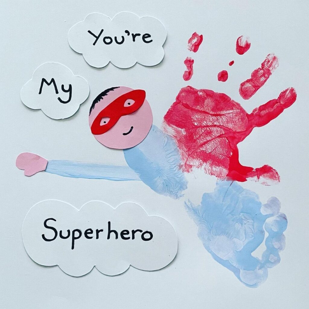 Superhero craft made from a red handprint, blue footprint, and paper cutouts.