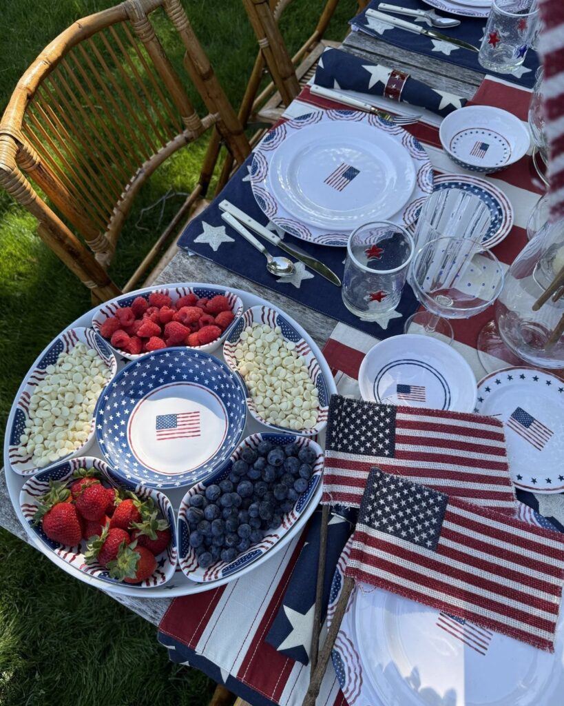 Patriotic table setting with red white and blue decor and a berry platter.