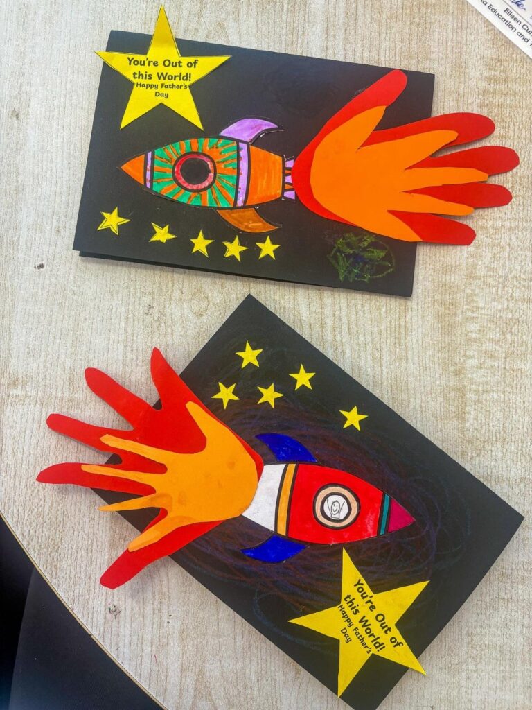 Two handmade Father's Day cards featuring rocket ships made from painted handprints.