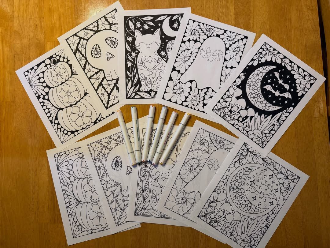 Halloween coloring pages with pumpkins and ghosts and white markers on wooden table