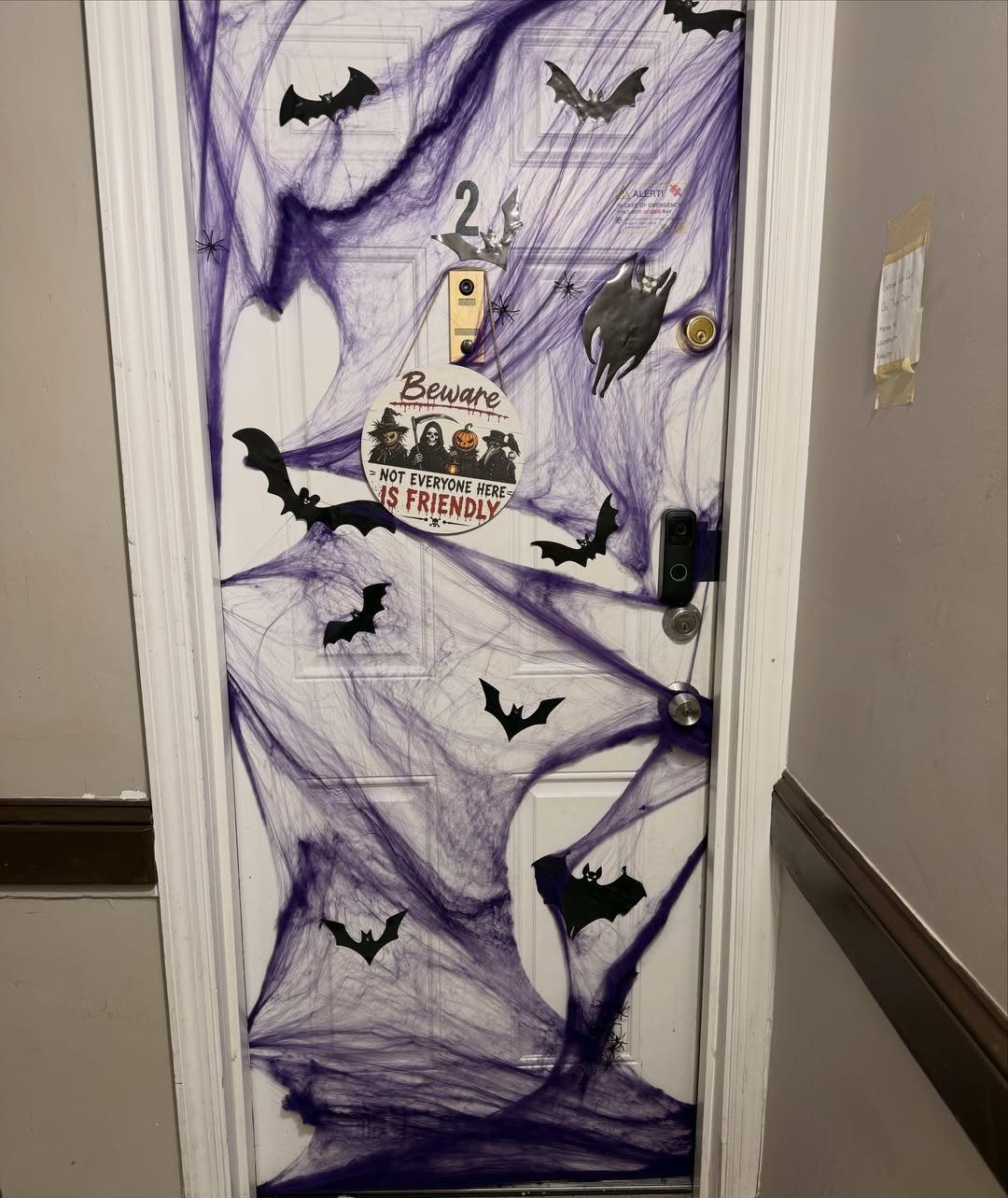 White door covered in purple spider webs and black bat silhouettes for Halloween.
