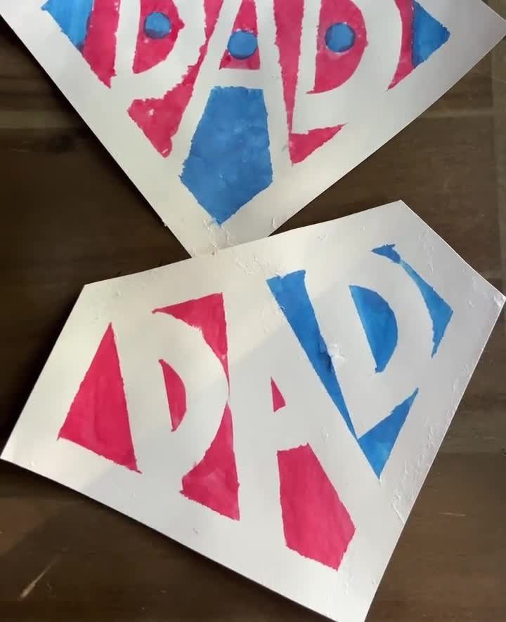 Two handmade cardboard signs with the word DAD painted in red and blue.