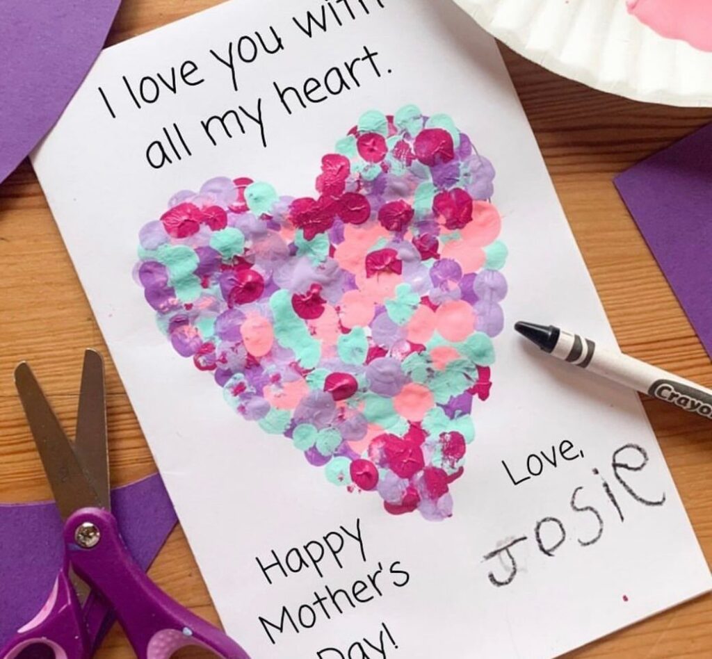 Handmade Mother's Day card with a colorful dotted heart and craft supplies.