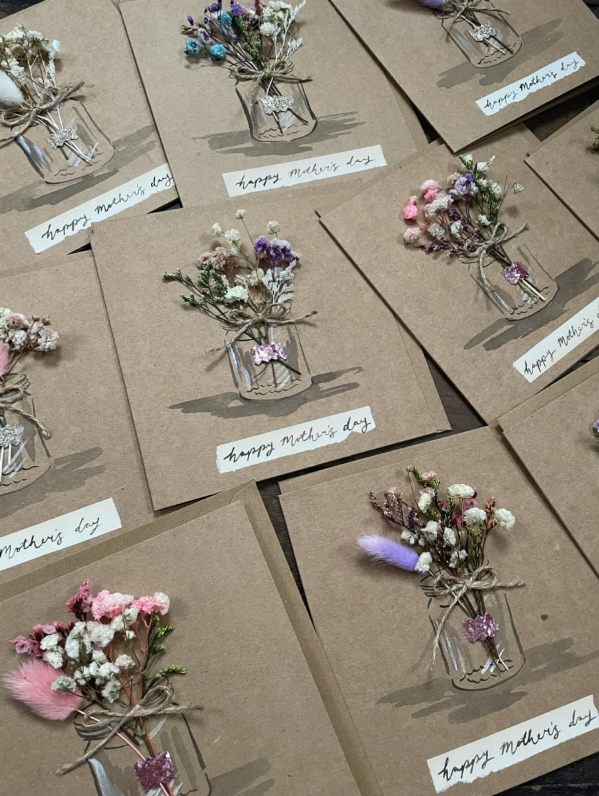 Brown kraft paper Mother's Day cards with small glass vials of dried flowers.