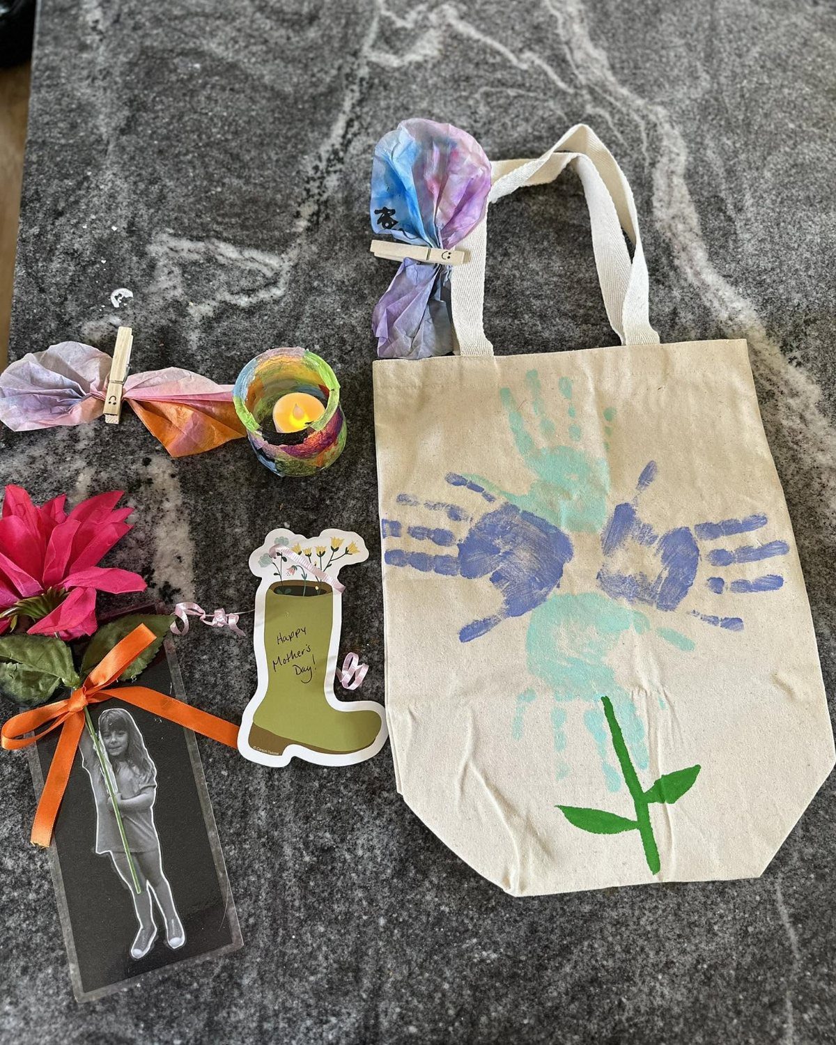 Handmade children's crafts including a handprint tote bag and a boot cutout on marble.