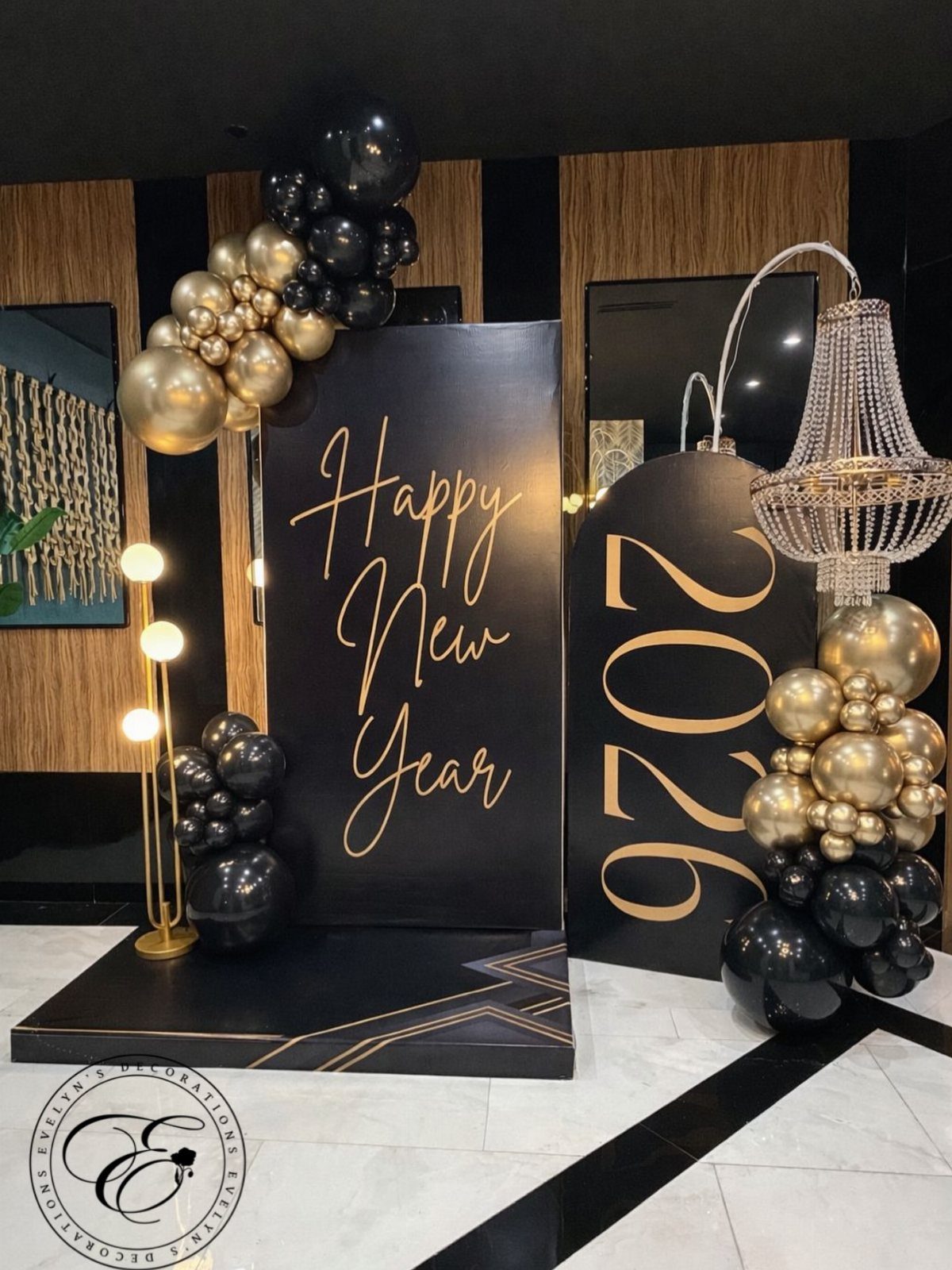 New Year's Eve decorations with black and gold balloons and a 2026 sign.