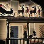Backlit silhouette of Santa in his sleigh pulled by reindeer on a roof