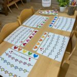 Heart pattern coloring pages and colored strips on a wooden classroom table.