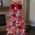 Christmas tree decorated with pink and red lollipop ornaments and a large red bow.