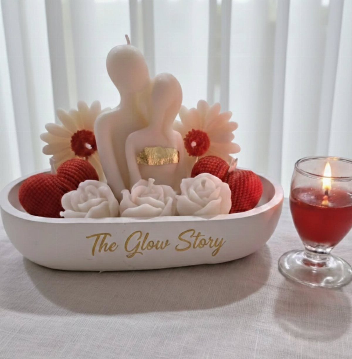 Couple-shaped white candle in a bowl with red hearts and white roses.