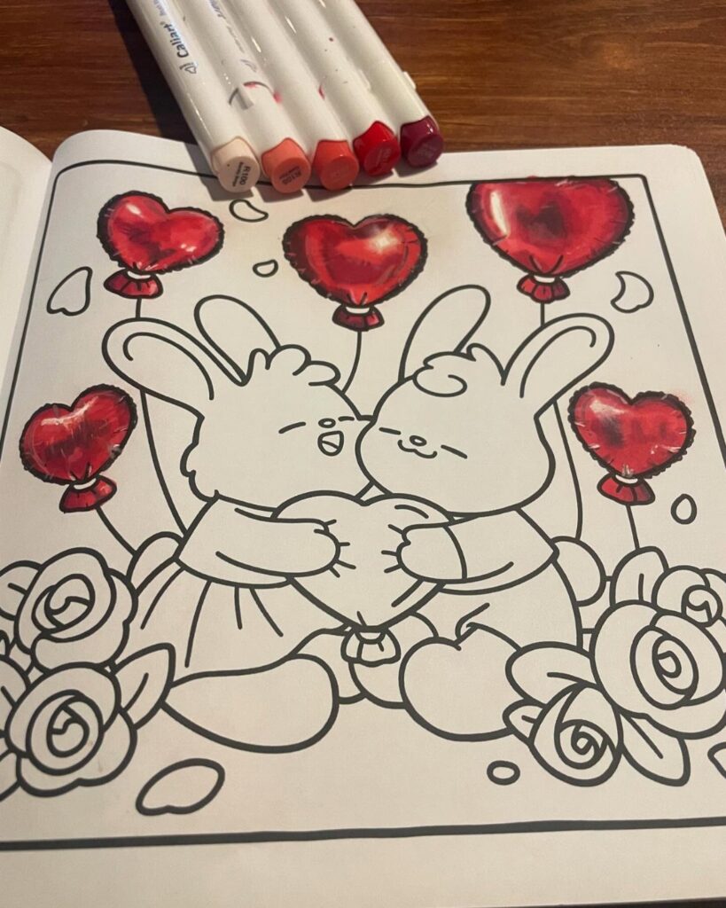 Two cartoon bunnies hugging a heart with red heart-shaped balloons and markers.
