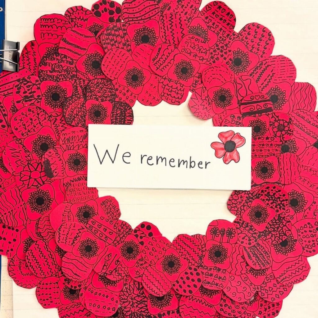 Red poppy wreath surrounding a white card that says We remember.